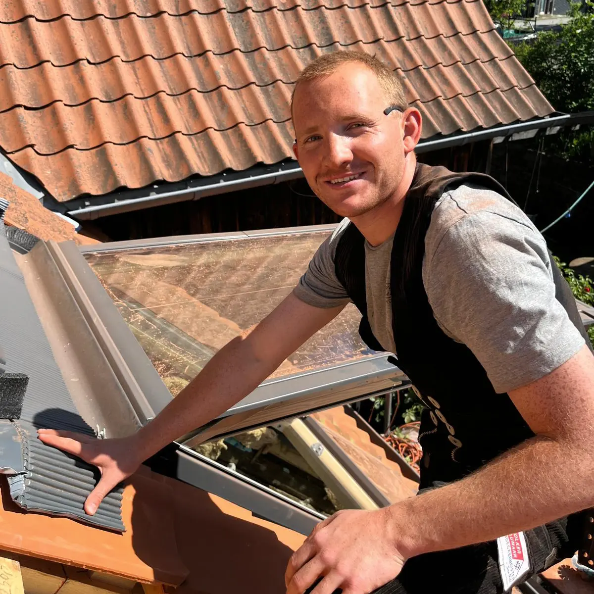 Azubi Sid Micklich ist Auszubildender bei Sven Hohl Dachdecker Meister aus Leichlingen. Auf dem Bild ist er bei der Arbeit auf dem Dach zu sehen und lächelt in die Kamera.